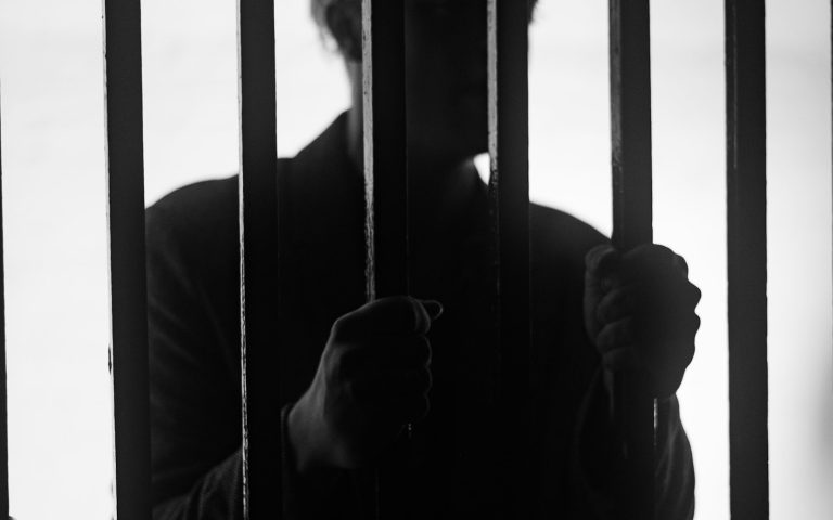 Hombre tras las rejas de una celda